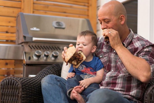 Man Feeding BBQ Burger to Toddler Son