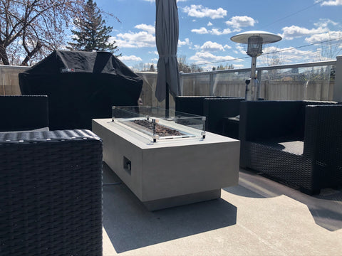 Thick concrete linear fire table with sleek straight sides and a long rectangular flame in the middle. This fire table has wide edges for glassware and fits perfectly on a deck or tight space. Available at Barbecues Galore: Burlington, Oakville, Etobicoke & Calgary