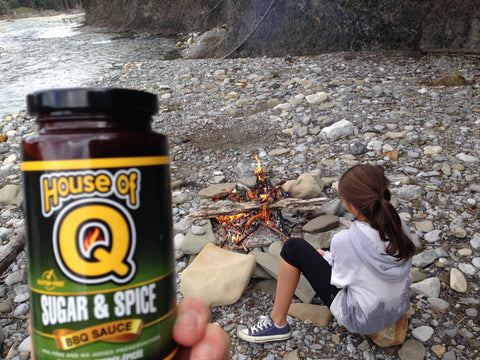 Girl enjoying House of Q Sugar & Spice BBQ Sauce on campfire smokies